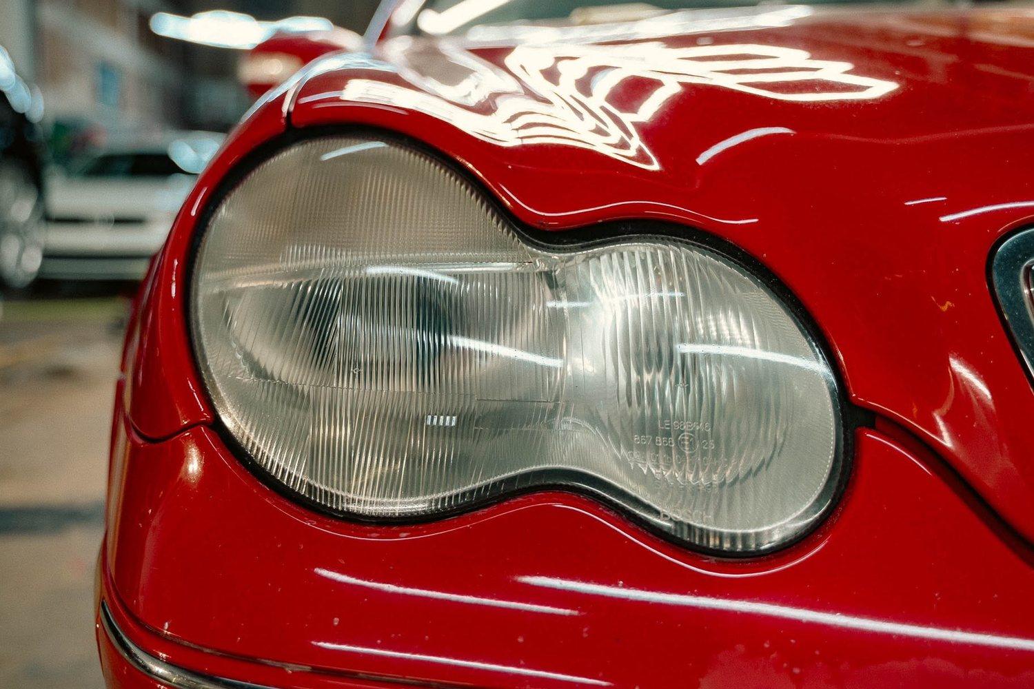 Clear restored headlight on a red Mercedes after restoration at Slick Auto Care Little Rock