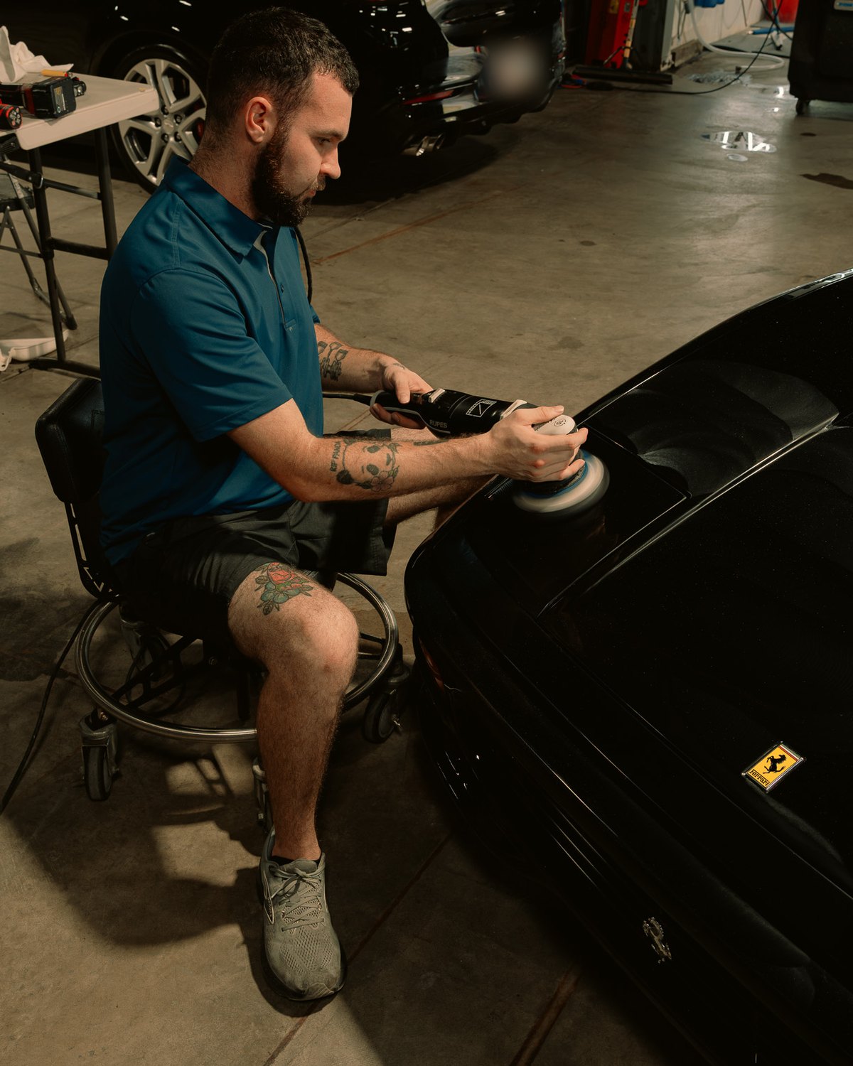 Slick Auto Care technician machine polishing a black Ferrari 355 in the shop in Little Rock AR